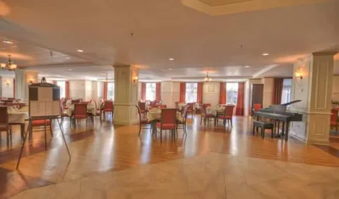 Dining room with set tables, red chairs, wooden flooring and a grand piano