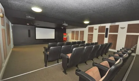 Rows of black cinema chairs facing a white projection screen