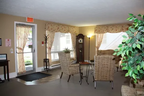 Room with wicker armchairs, a small table and tall windows