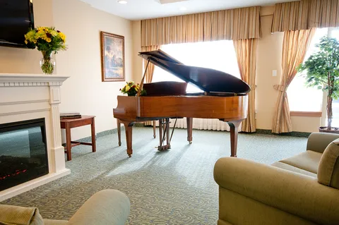 Lounge with a grand piano, fireplace and armchairs.