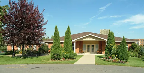 Front entrance of the residence beside trees and planted shrubs.
