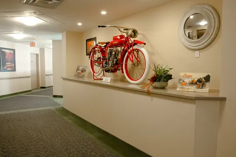 Hallway display with a red bicycle and framed pictures.