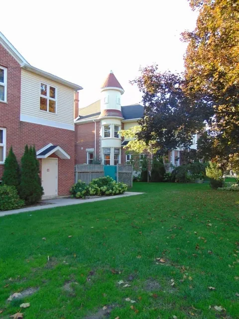 Brick residence with a rounded tower beside a lawn and autumn trees