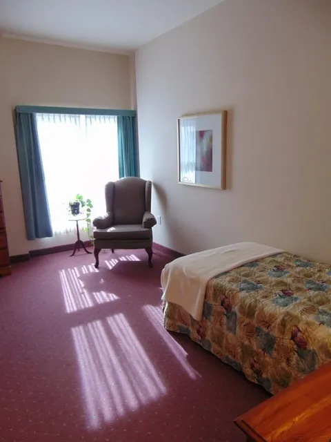 Bedroom with a bed, armchair and curtained window