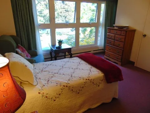 Bedroom with a bed, wooden dresser and large windows
