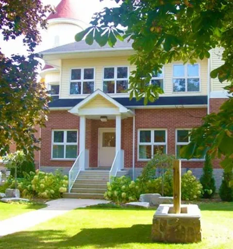 Covered entrance with steps, railings and flowering shrubs