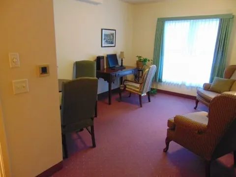 Room with a desk, chairs, computer and large curtained window