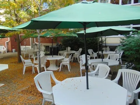 Patio with white tables and chairs beneath green umbrellas