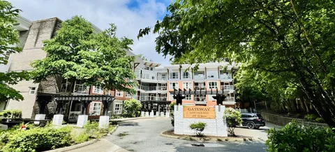 Residence buildings viewed through trees from the driveway.