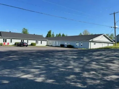 Residence wing beside a paved parking area and trees