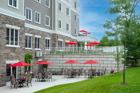 Residence beside a patio with red umbrellas and a lawn