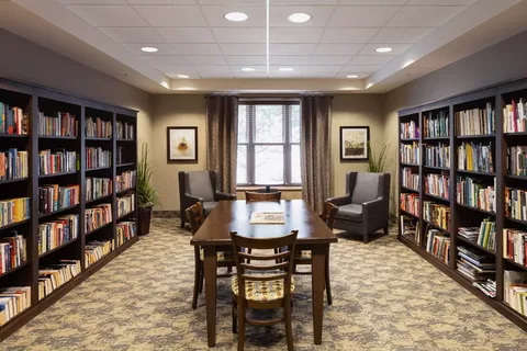 Library with bookshelves, a long table and armchairs