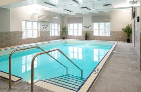 Indoor pool with steps, handrails and large windows