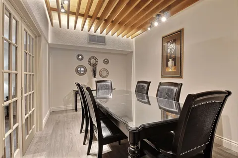 Dining room with a long table, upholstered chairs and a wood-beamed ceiling