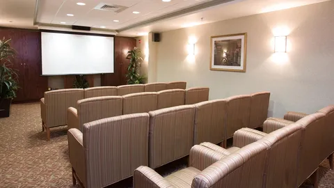 Cinema room with upholstered seating and projection screen.