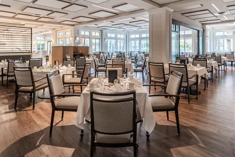 Dining table with white linen, upholstered chairs and place settings