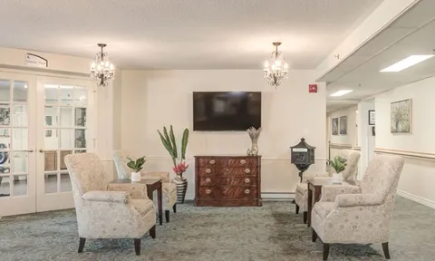 Lounge with armchairs, television and a wooden cabinet.