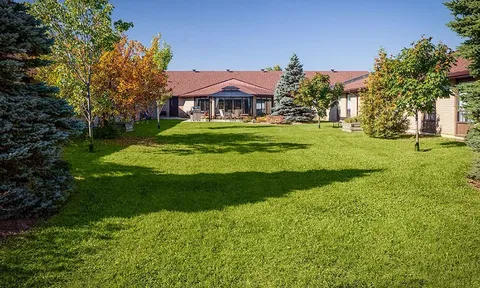 Broad lawn and mature trees beside the residence.
