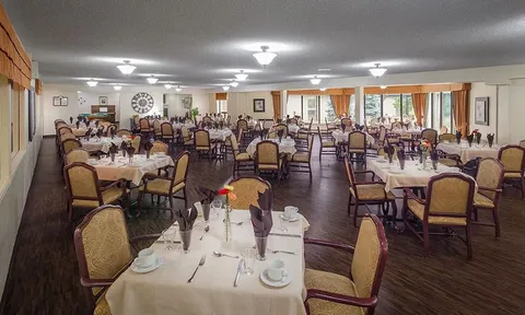 Dining room with set tables and upholstered chairs.