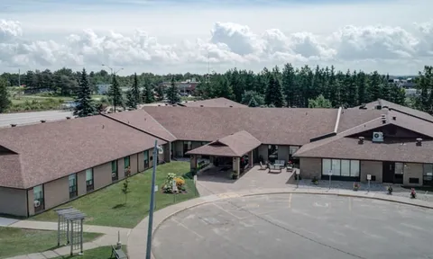 Aerial view of residence roofs, entrance and paved drive.