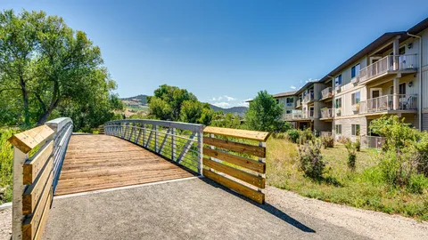 Wooden footbridge and path beside the residence and a creek.