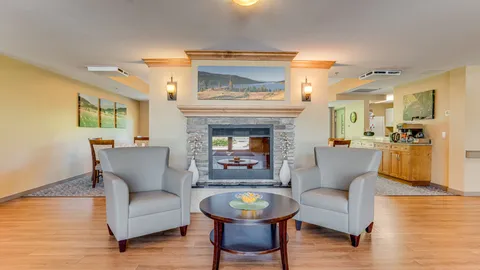 Sitting area with two armchairs and a stone fireplace.