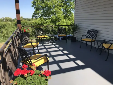 Balcony with chairs, flower pots and a railing overlooking trees