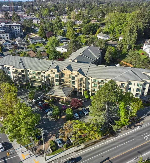 Aerial view of the residence, covered entrance, parked cars and surrounding trees.