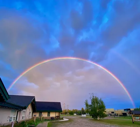 Residence buildings beside a gravel drive beneath a rainbow