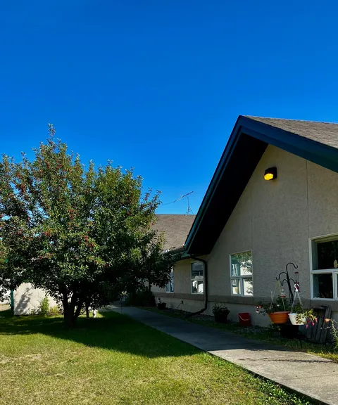 Residence exterior with grey walls, green roof trim, a lawn and concrete path