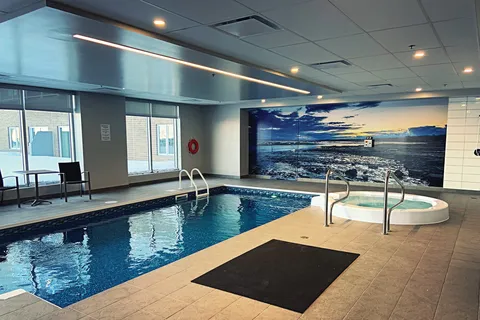 Indoor swimming pool and spa beside a landscape wall mural.