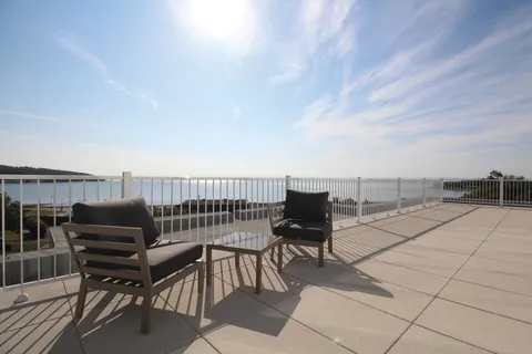 Terrace with chairs and a view toward the water.