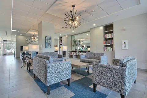 Lounge with patterned sofas, bookshelves and pendant lights.