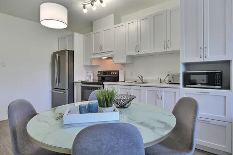Suite kitchen and dining table with white cupboards.