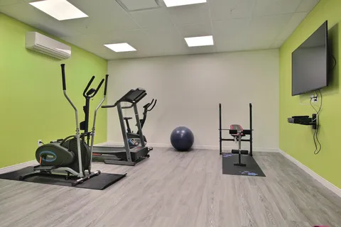 Fitness room with exercise equipment and green walls.