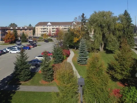 Buildings and parking beside landscaped grounds with paths and trees