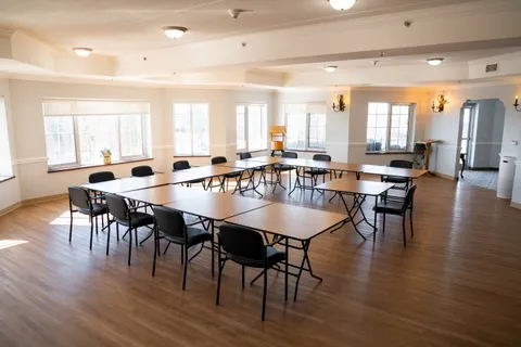 Room with tables and chairs beside large windows