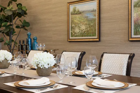 Private dining table set with plates and glassware beneath framed artwork.