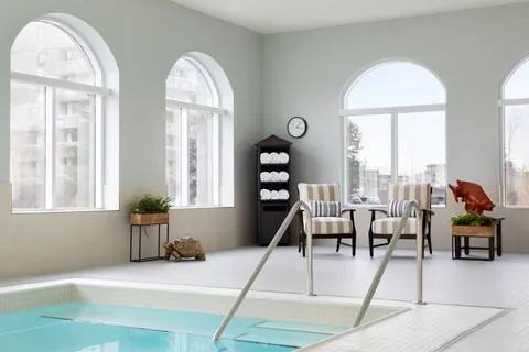 Indoor pool with arched windows and poolside seating.