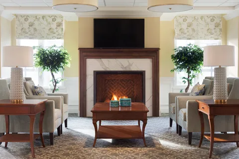Lounge chairs and coffee table beside a fireplace and television.