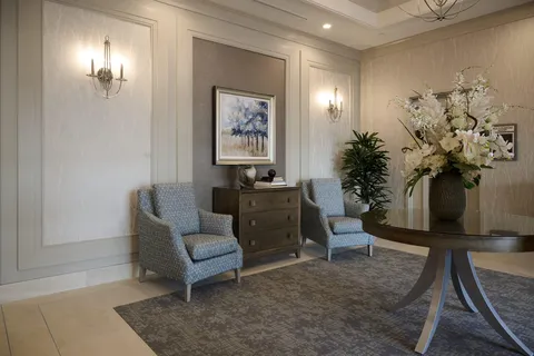 Seating alcove with two blue chairs, a table and landscape artwork