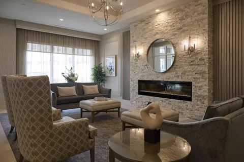 Room with armchairs, a sofa, a stone fireplace and a round mirror