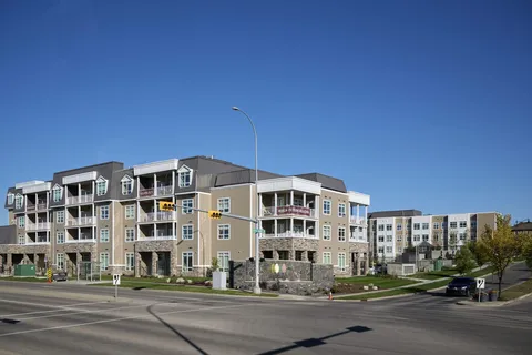 Multi-storey building with balconies and stone cladding beside a road