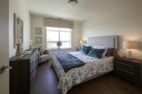 Bedroom with floral bedding, teal pillows, a dresser and a wall mirror