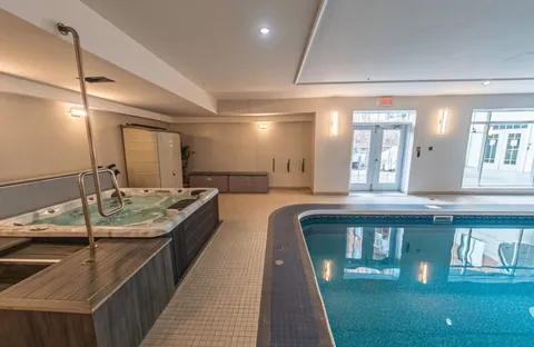 Indoor swimming pool and whirlpool with handrails and tiled surrounds