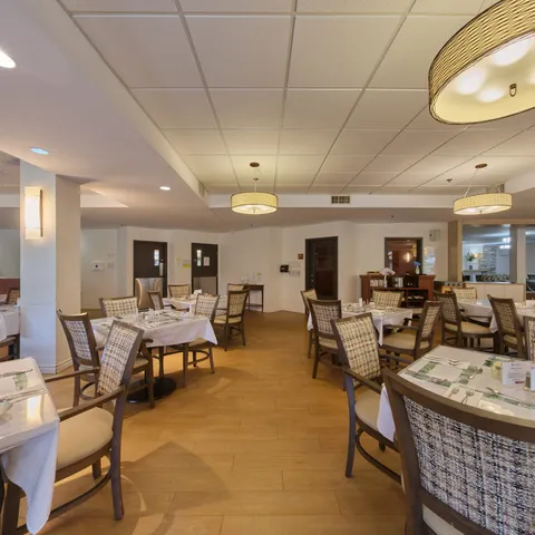 Dining room with set tables, upholstered chairs and hanging lamps
