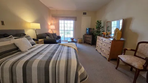 Suite with a bed, sofa, dressers and balcony doors.