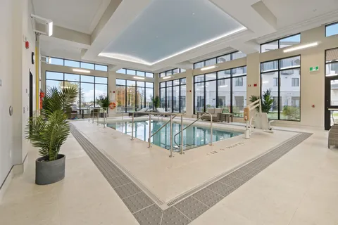 Indoor swimming pool beside tall glass walls