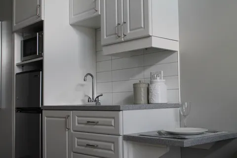 Kitchenette with white cabinets and tiled backsplash