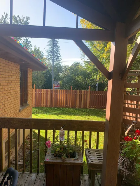 Garden lawn, fence and flowering plants seen from a covered deck